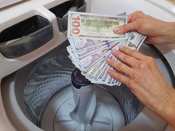 A person holding $100 bills over a washer